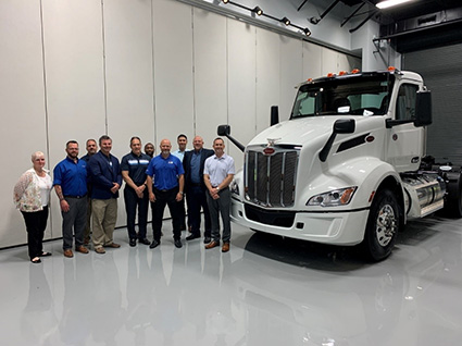 Aim leaders and representatives of Peterbilt/PACCAR stand next to a fresh-off-the-line Peterbilt Model 579, which will join the ranks of Aim's robust rental fleet.